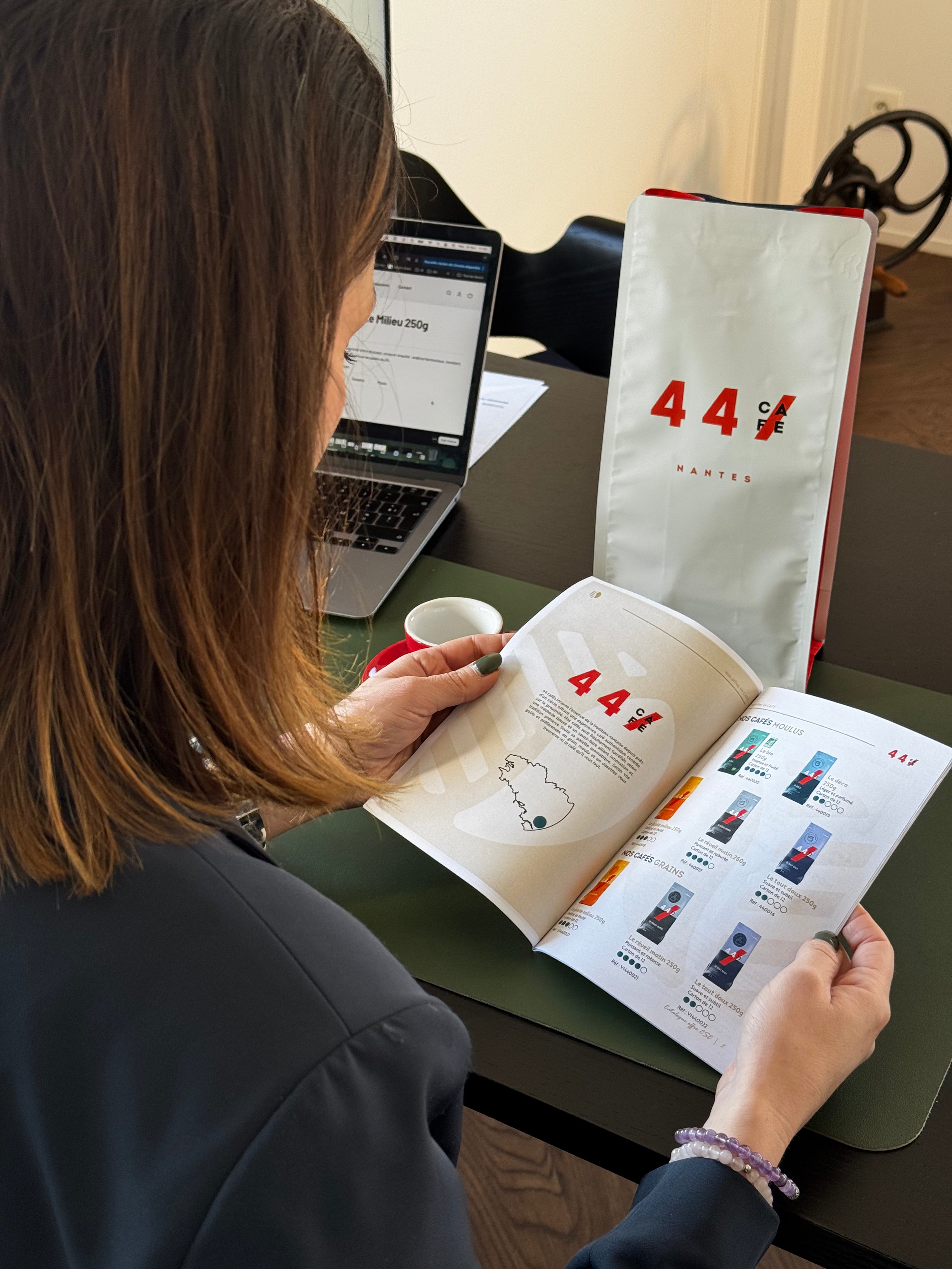Femme consultant une brochure 44Café à côté d'un paquet de café et d'une tasse